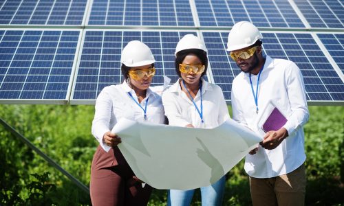 African american technician checks the maintenance of the solar panels. Group of three black engineers meeting at solar station.